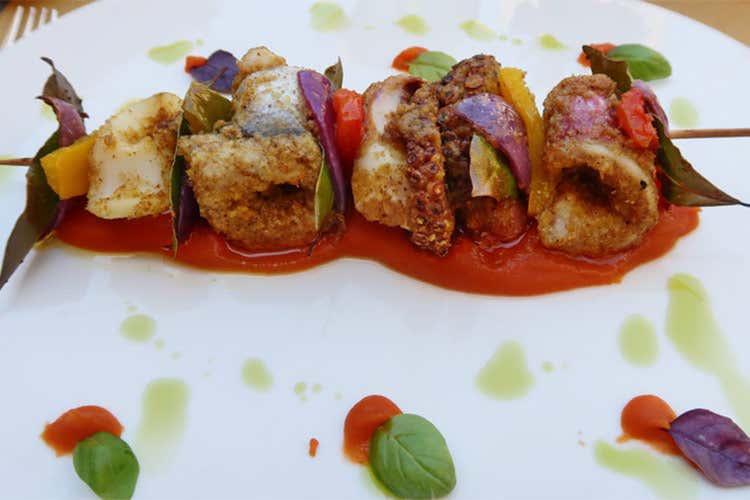 Spiedino di pescato del giorno: polpo, calamaro, involtini di triglia e merluzzo con tre peperoni su purea di patate al peperone rosso e curry rosso