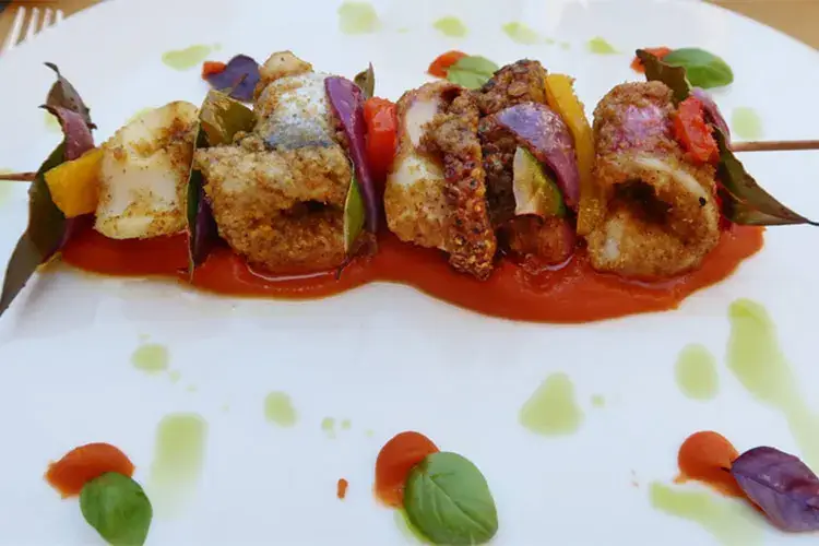 Spiedino di pescato del giorno: polpo, calamaro, involtini di triglia e merluzzo con tre peperoni su purea di patate al peperone rosso e curry rosso