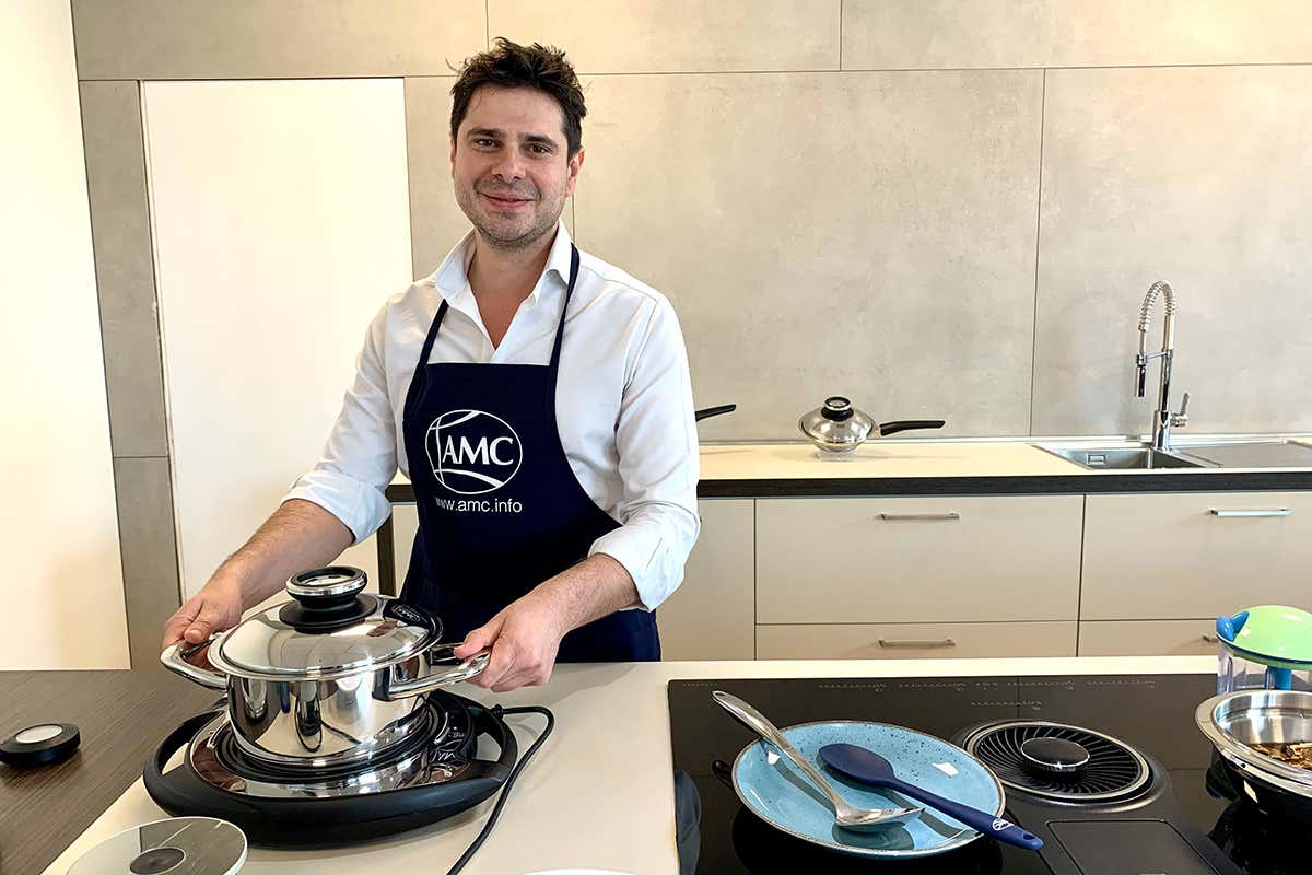 Andrea Pedrono con una pentola in acciaio inox Amc sul piano di cottura mobile Navigenio Pentole in acciaio inox e sistemi di cottura Amc per risparmiare tempo ed energia