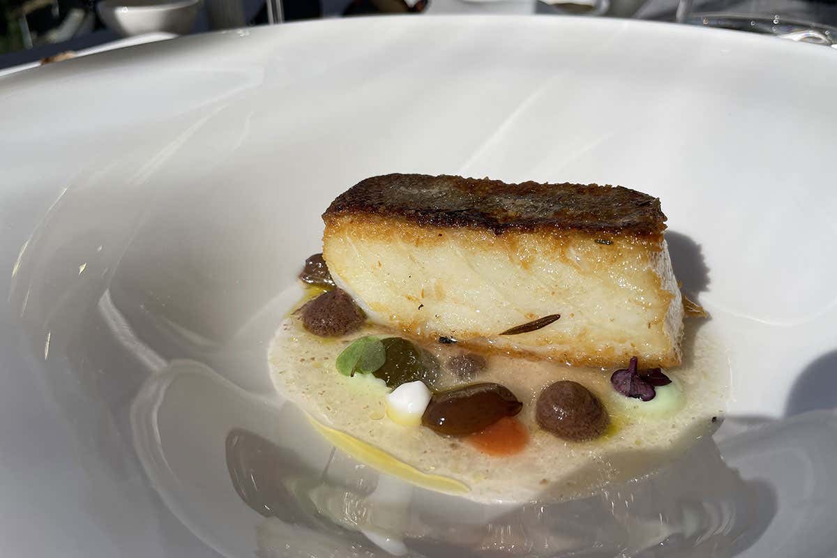Filetto di baccal&agrave; affumicato con erbe aromatiche, affumicato e impiattato al tavolo con condimenti come salicornia, cappero e una purea di olive taggiasche