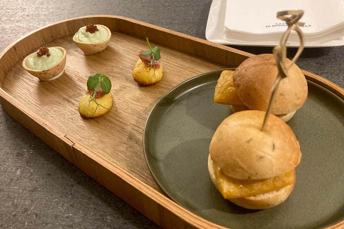 Un primo assaggio: la tartelletta alla ricotta al basilico con perlage di acciuga e il bignè fritto con tartare di tonno rosso, in equilibrio tra acidità e dolcezza