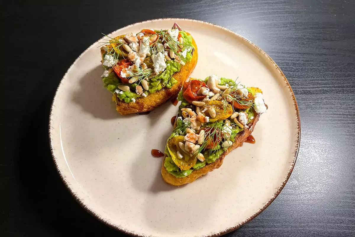 Avocado toast con feta, pinoli, pomodorini confit e sciroppo di melograno 