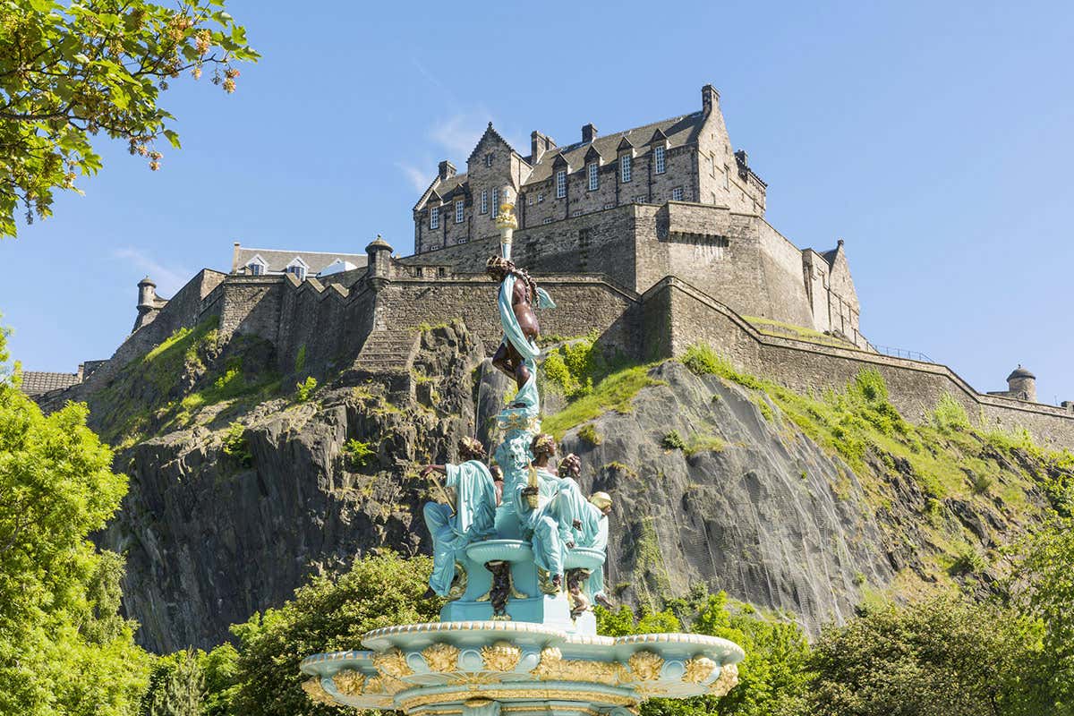 La monumentale Ross Fountain nei Princes Street Gardens, con l'imponente fortezza del Castello di Edimburgo arroccata sulla roccia vulcanica a fare da sfondo