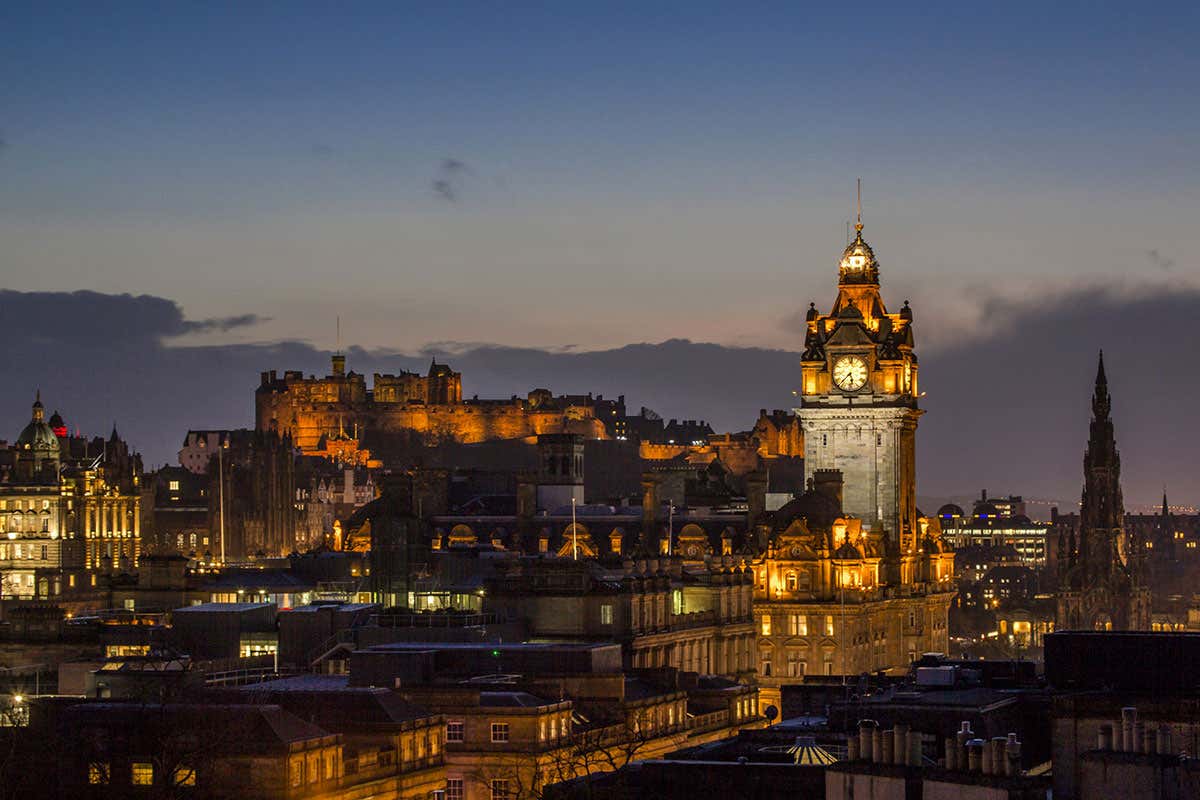 Lo skyline di Edimburgo illuminato all'imbrunire, con le luci del Castello e della New Town che si stagliano contro il cielo della sera