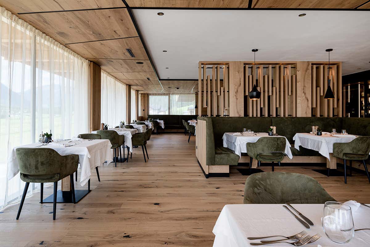 La sala ristorante dell'Alpine Nature Hotel Stoll, dove l'illuminazione studiata e le ampie vetrate accompagnano l'esperienza culinaria legata alla biodiversità del territorio