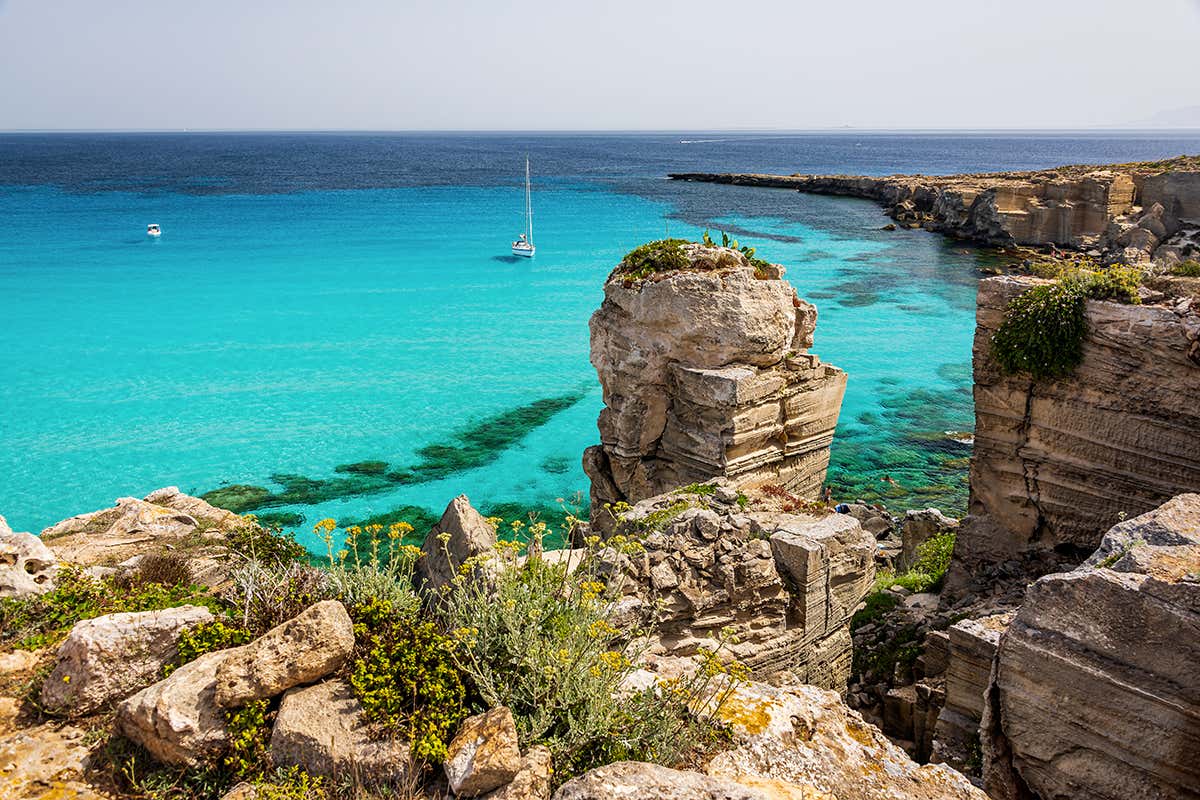La spettacolare baia di Cala Rossa, dove il bianco accecante delle antiche cave di tufo abbraccia una delle acque più trasparenti e fotografate del Mediterraneo