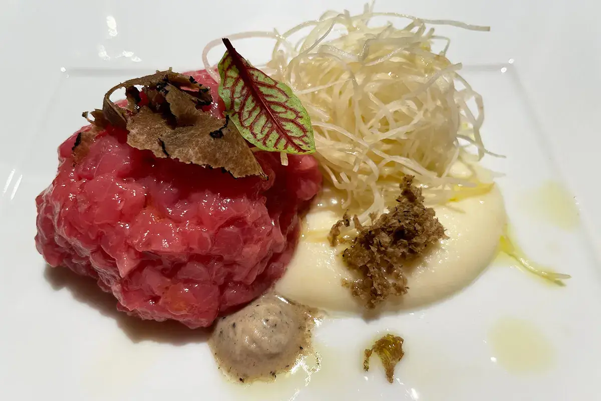 Battuta di carne cruda di “Vicciola” (allevata con nocciole) con tartufo nero e sedano rapa Dall'hotel alla Loge sui campi da sci, [Le Massif vince anche grazie all'alta cucina]