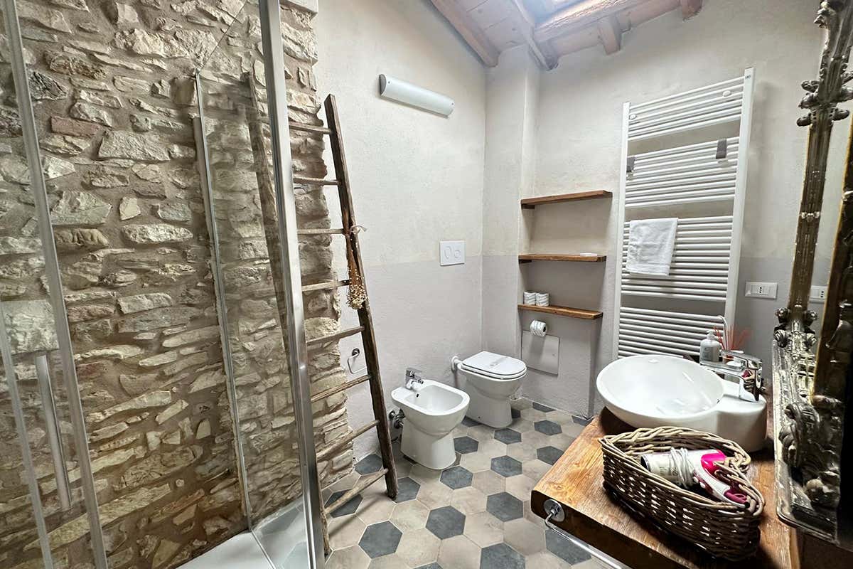 Cura del dettaglio anche nella sala da bagno, dove la matericità della pietra a vista dialoga con elementi di recupero e specchiere d'epoca