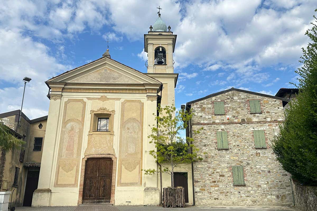 Il cuore di Golferenzo: la facciata affrescata della chiesa parrocchiale affiancata dalle splendide dimore in sasso di Golferenzo