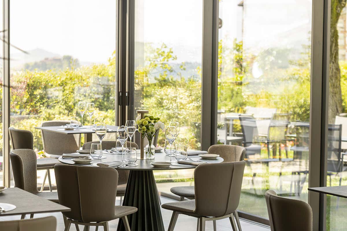 L'atmosfera sospesa e luminosa della sala de La Corte: ideale per farsi guidare nei percorsi di gusto del relais, circondati dal verde rigoglioso delle colline