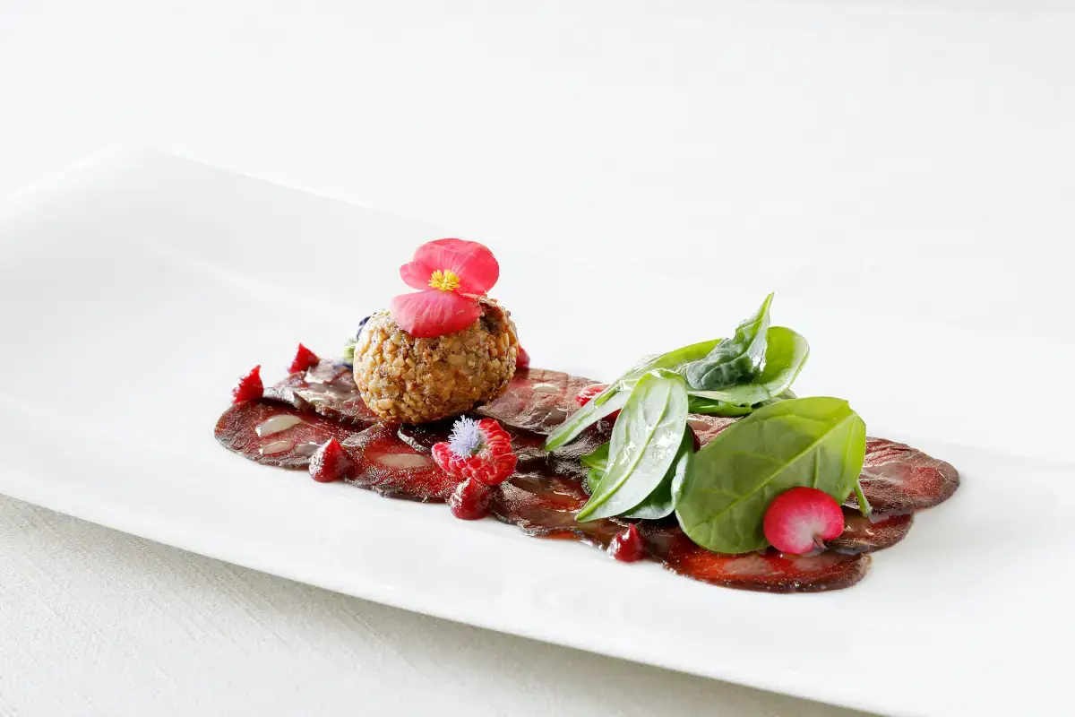 Carpaccio di cervo marinato al ginepro con il suo bon bon in crosta di nocciola