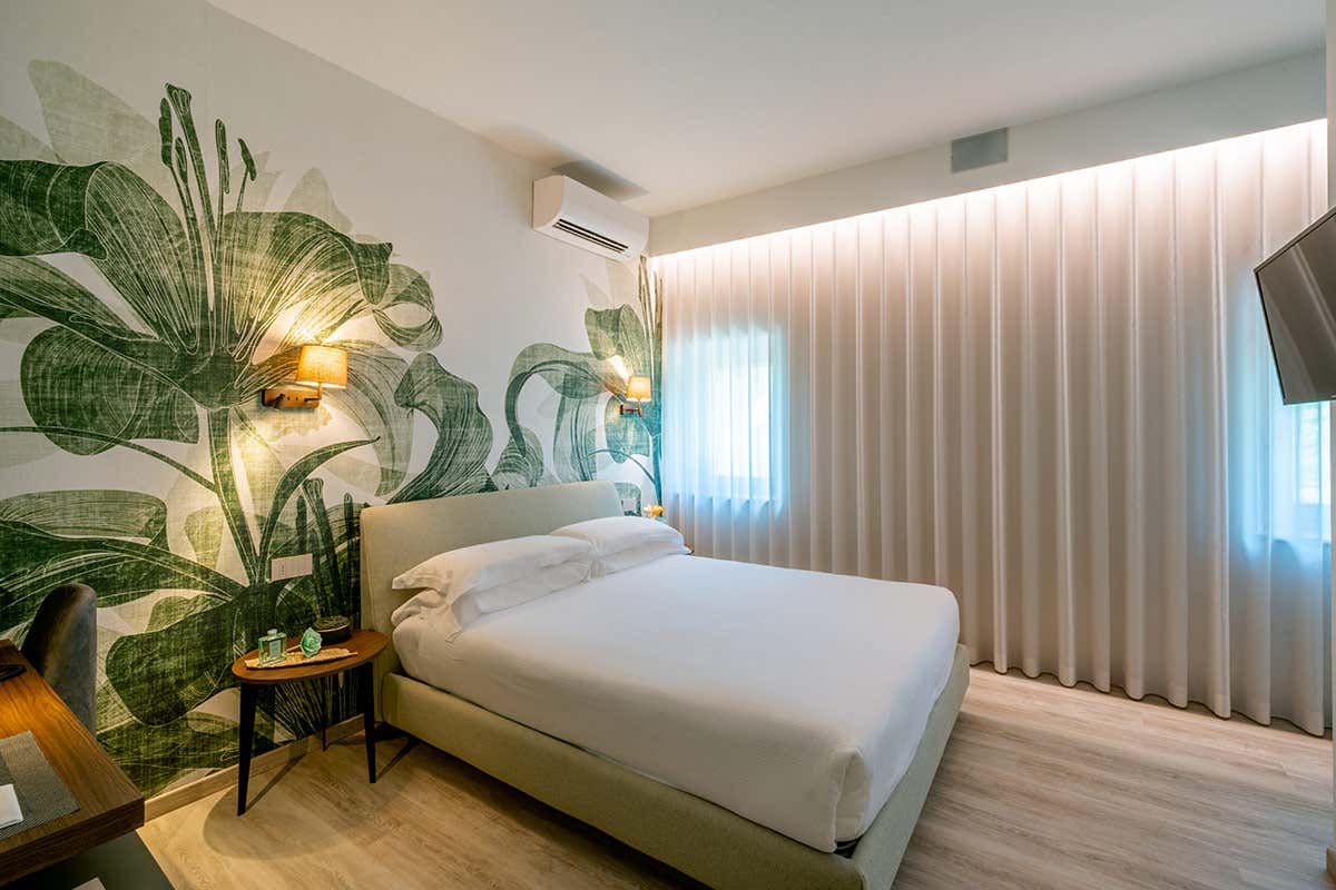 Un dettaglio delle camere da letto di charme, caratterizzate da arredi contemporanei in legno e pareti artistiche ispirate alla flora locale