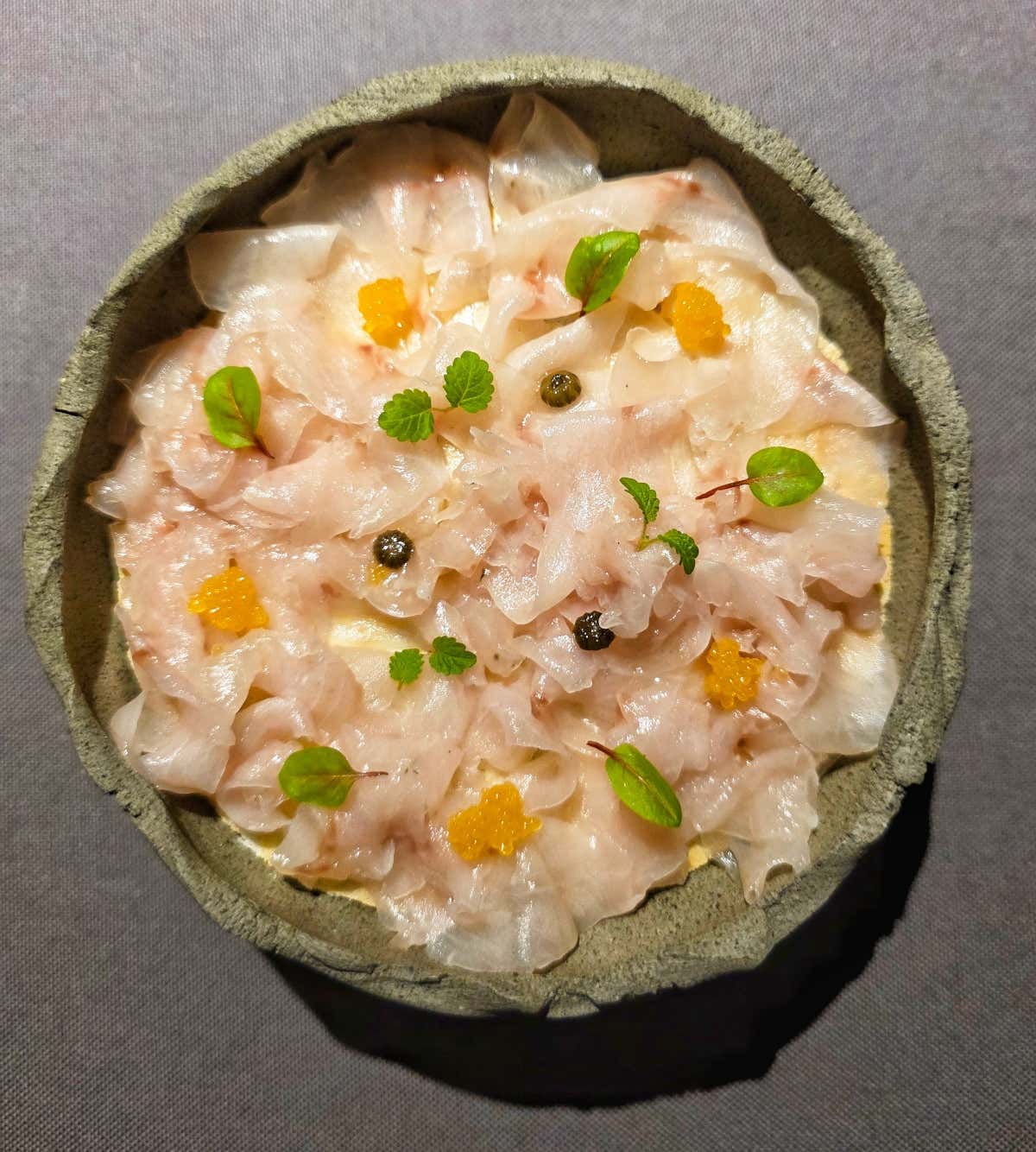 Salmerino marinato con levistico e prezzemolo, servito con le sue uova, capperi di margherita, germogli, una cialda all’abete e un’emulsione di miso di nocciole e abete