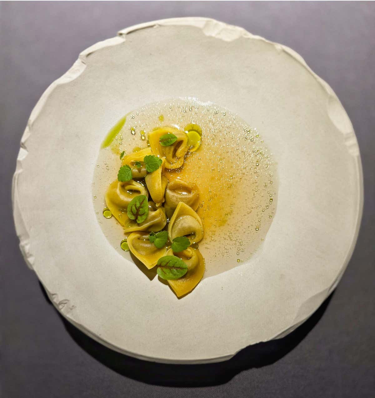 Tortellini ripieni di cinghiale, stravecchio di Sauris, con alla base gocce di sciroppo di pino mugo, fondo di cervo e olio al levistico, con un infuso di fieno di primo taglio