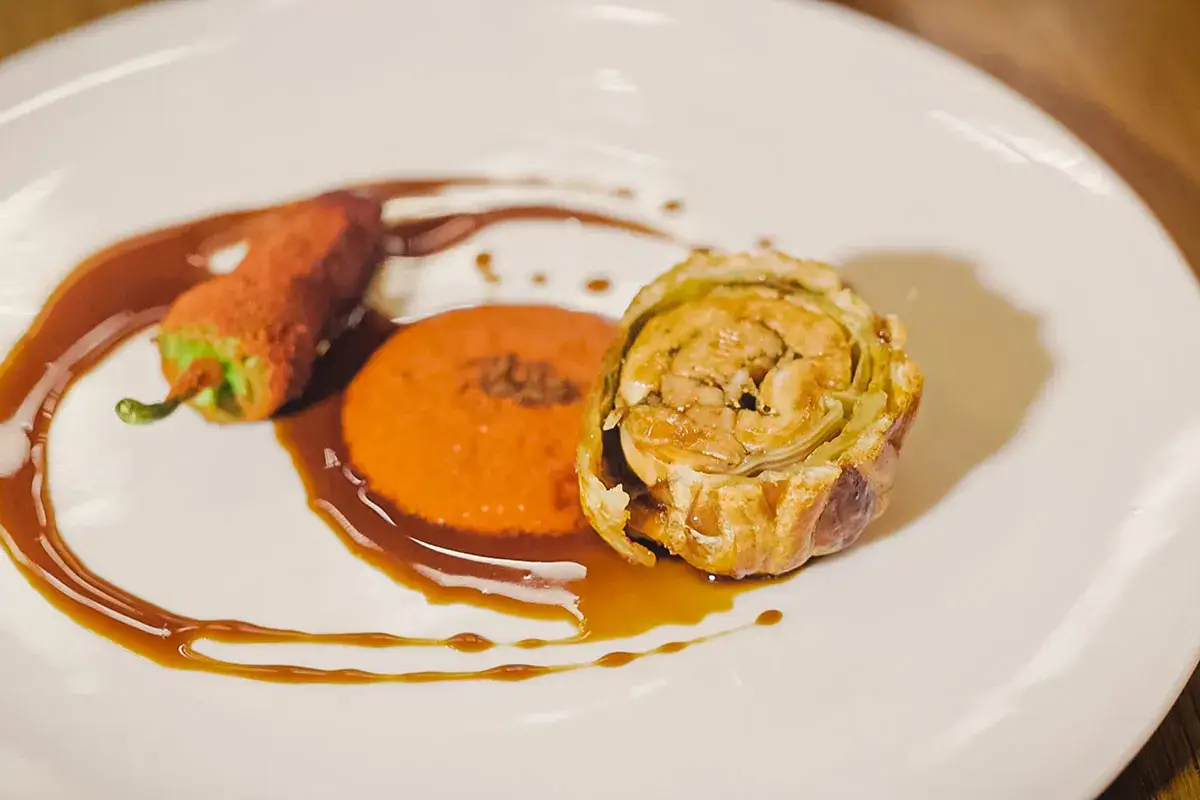 Coniglio grigio di Carmagnola alla Wellington, scarola brasata e ketchup di peperoni rossi affumicato (credito foto: Simona Bruno) Il Coniglio alla Wellington di Postorino con Monsieur di Prime Alture: trionfo di sapori