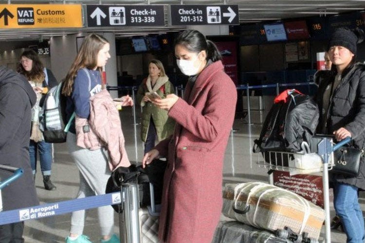 Turisti cinesi con mascherina in aeroporto (Il virus cinese smorza il turismo Preoccupazione tra gli albergatori)