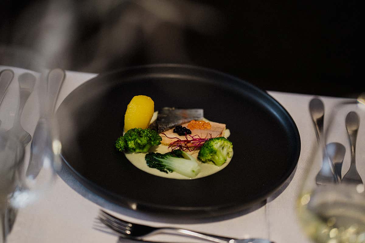 elegante secondo piatto a base di pesce d'acqua dolce con uova di storione, verdure croccanti e patata tornita, servito durante la cena gourmet