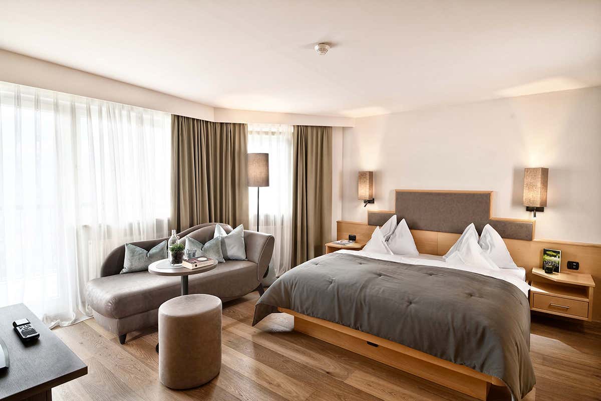 Le ampie camere dell'hotel coniugano arredi essenziali in materiali naturali e grandi vetrate affacciate sul paesaggio della Val Venosta