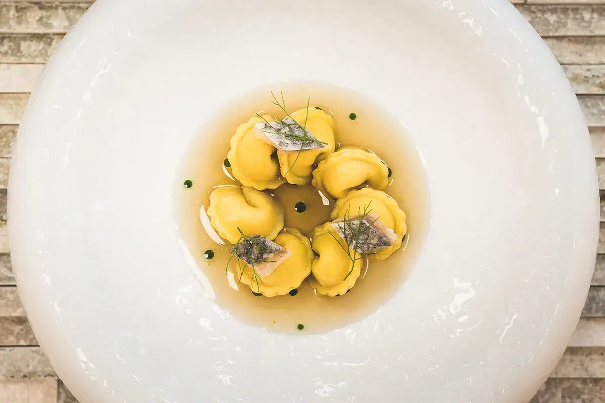 Tortellini di melanzane alla brace con dashi alle acciughe e branzino in crudité Katsuobushi, un concentrato di gusto che esalta la cucina fusion