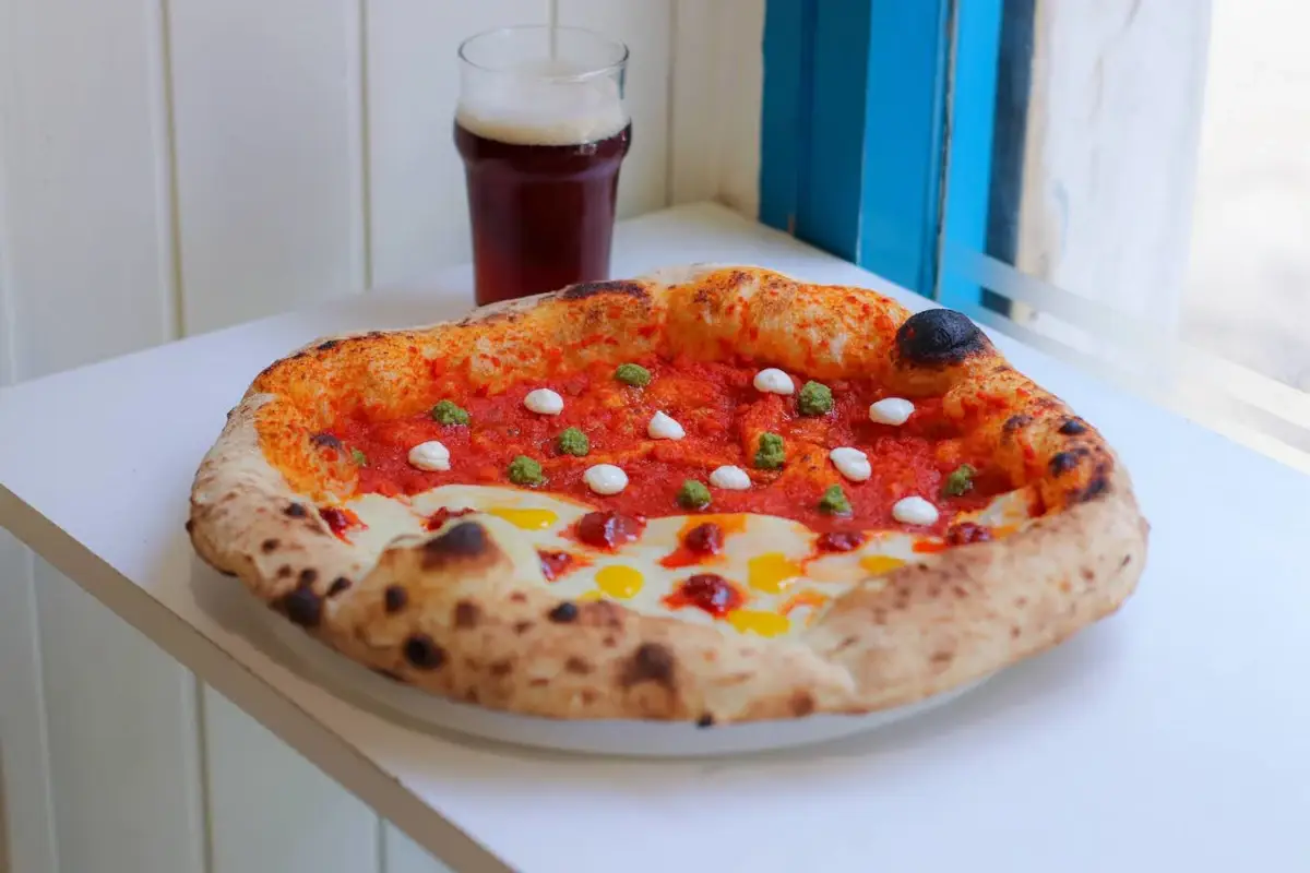 La nuova pizza firmata Favur&igrave;: una doppia base di crema di patate e sugo di pomodoro accoglie gocce di &lsquo;nduja, crema di fiordilatte, pesto di basilico, carbocrema e pesto di pistacchi 