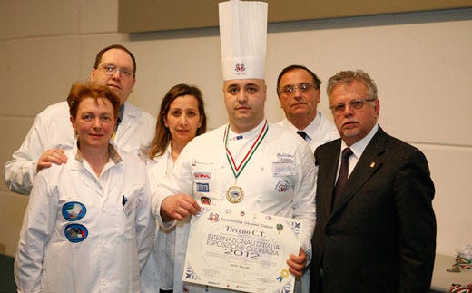 Mauro Bellomo, al centro, premiato al merito da Paolo Caldana, a destra