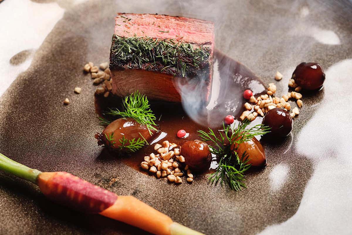 Filetto di cervo in crosta di aneto col suo juice al pepe rosa, accompagnato da cipolline cotte in aceto di Modena, granella di mandorle pralinate salate e carotine di Putignano Il bello della neve a marzo al Bonfanti Design Hotel di Chienes