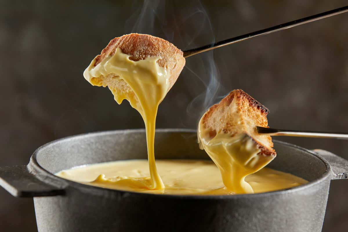 La fondue si gusta immergendo il pane nel formaggio fuso
