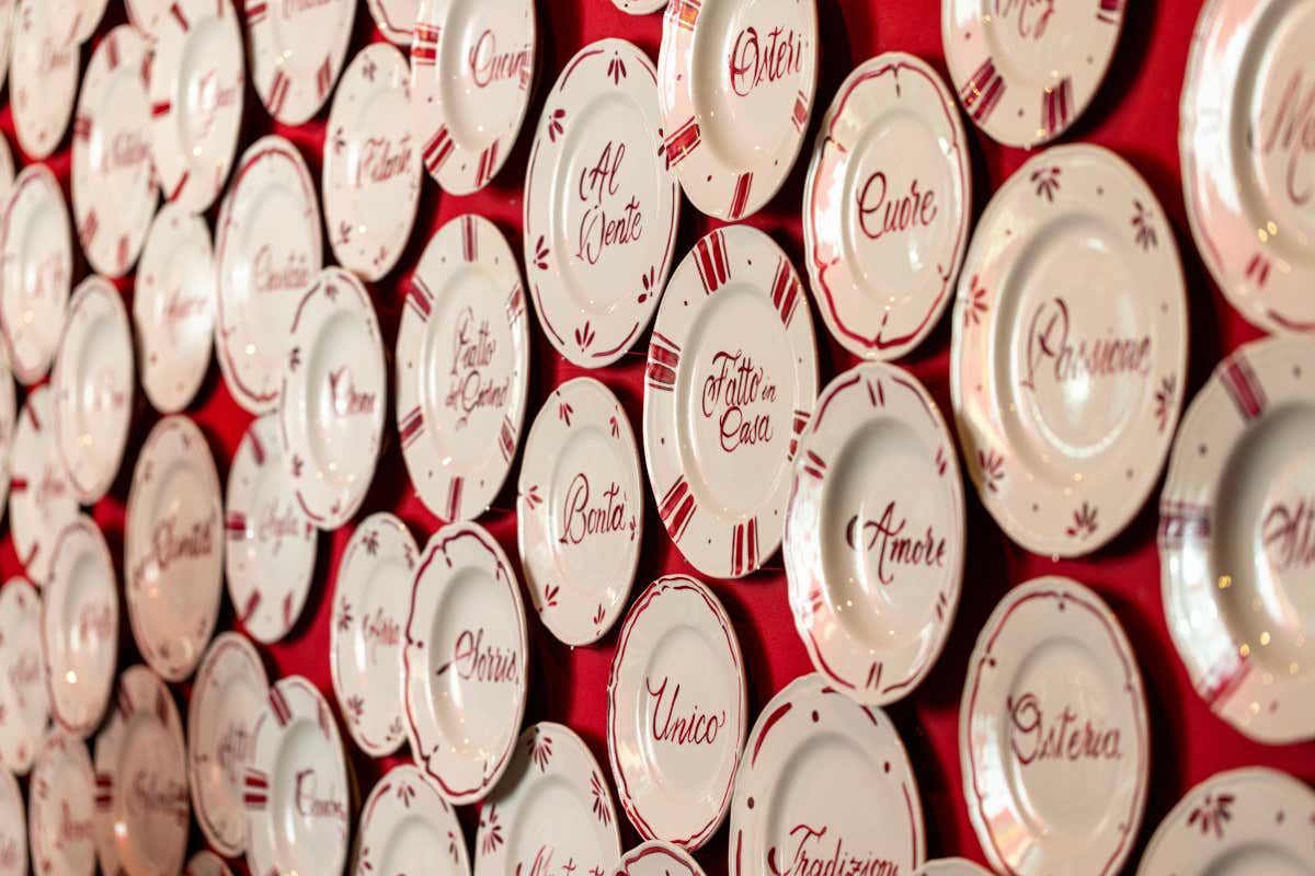 Il “muro di parole”, una parete con piatti appesi e frasi poetiche realizzate dall’artista Allegra Calligrafia