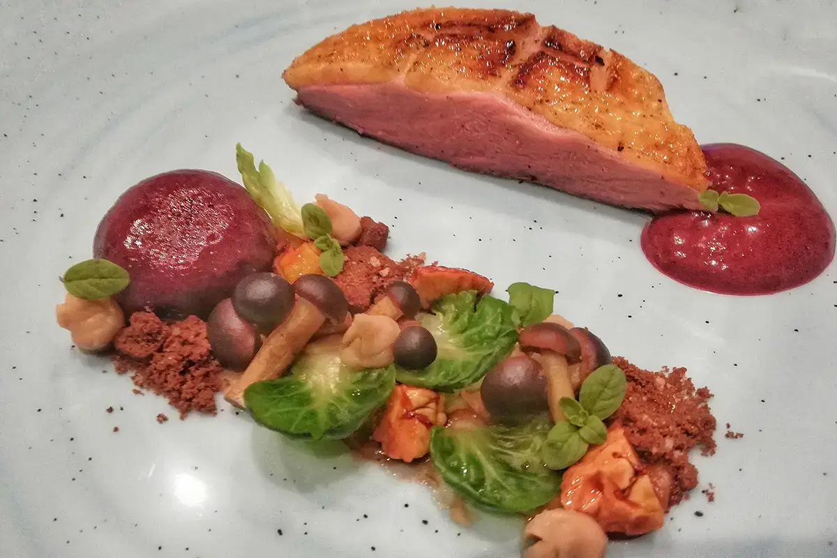 Petto d&lsquo;anatra laccato, crumble al cioccolato e maggiorana, crema di castagne, castagne glassate al marsala pioppini e cavoletti ripassati Anatra laccata, cioccolato, castagne e pioppini