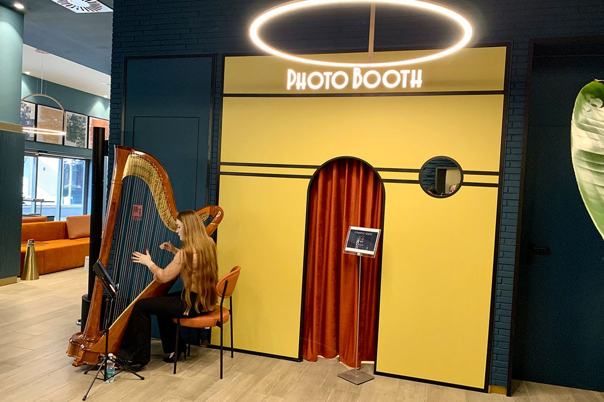 Un'arpista di fronte allo spazio Photo Booth Debutta il Duo Milan Porta Nuova il “bleisure hotel”