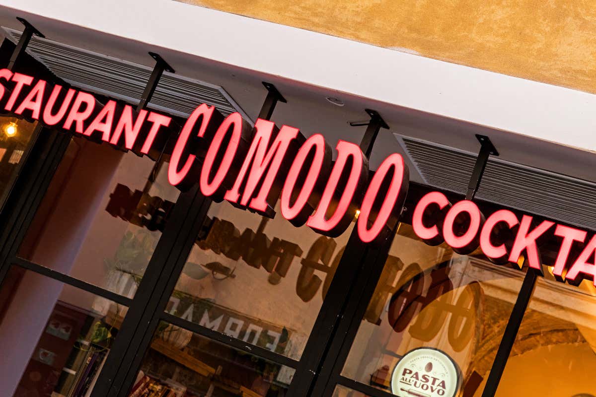 L'insegna in esterno di Comodo Apre Comodo, un'officina del gusto nel cuore della Capitale