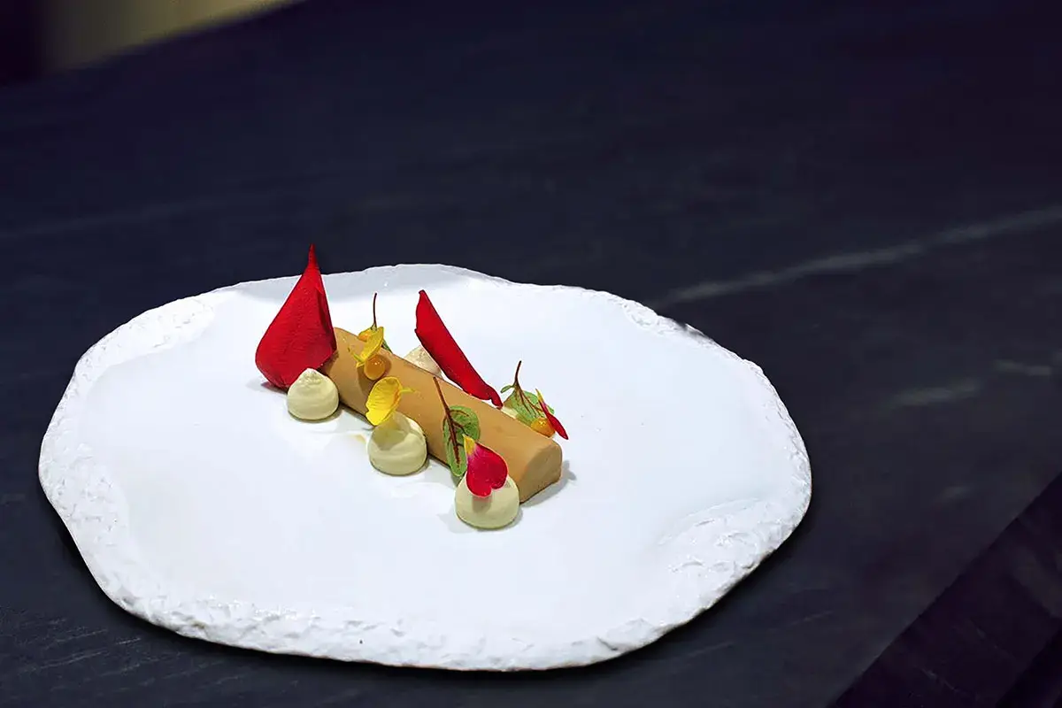 Bavarese alla liquirizia con namelaka al cioccolato bianco, rose rosse e olio extravergine, gel di kumquat alle rose Bavarese alla liquirizia con namelaka al cioccolato bianco e gel di kumquat alle rose