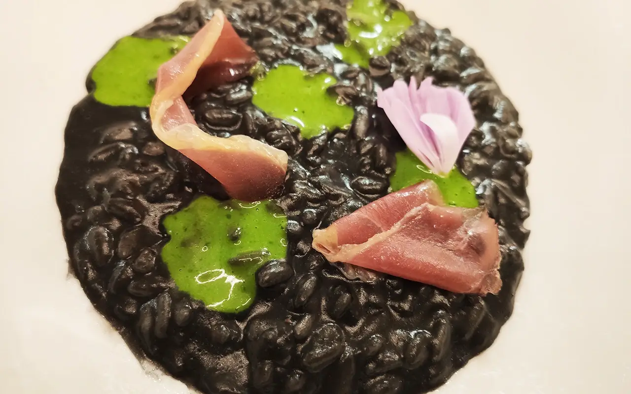 Risotto all’aglio nero fermentato, prezzemolo e speck d’anatra Disegna la tua vacanza sulle Dolomiti: le novità del Bonfanti di Chienes