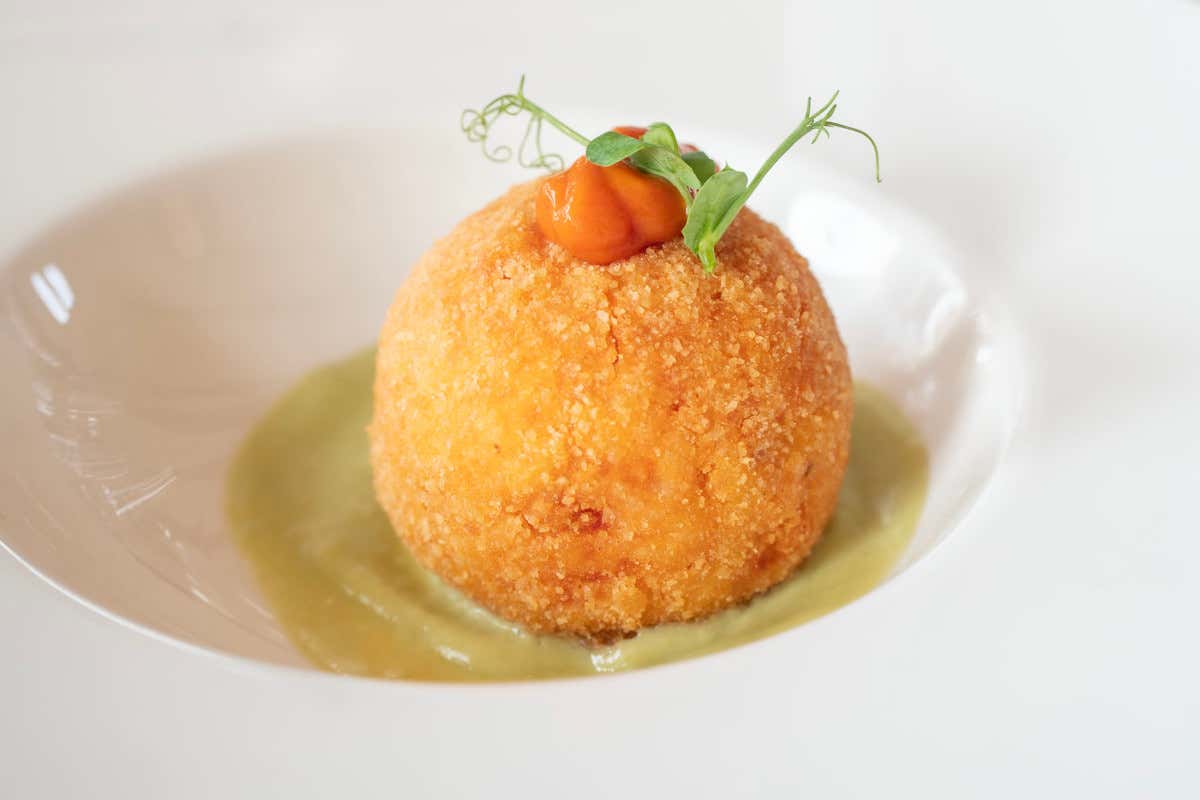 L’arancino al pomodoro, con cuore di mozzarella e vellutata al basilico, realizzato con riso S. Andrea Dop