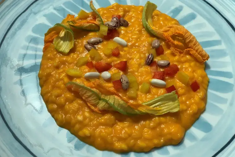 Risotto mantecato con estratto di calore, fiori di zucca e legumi