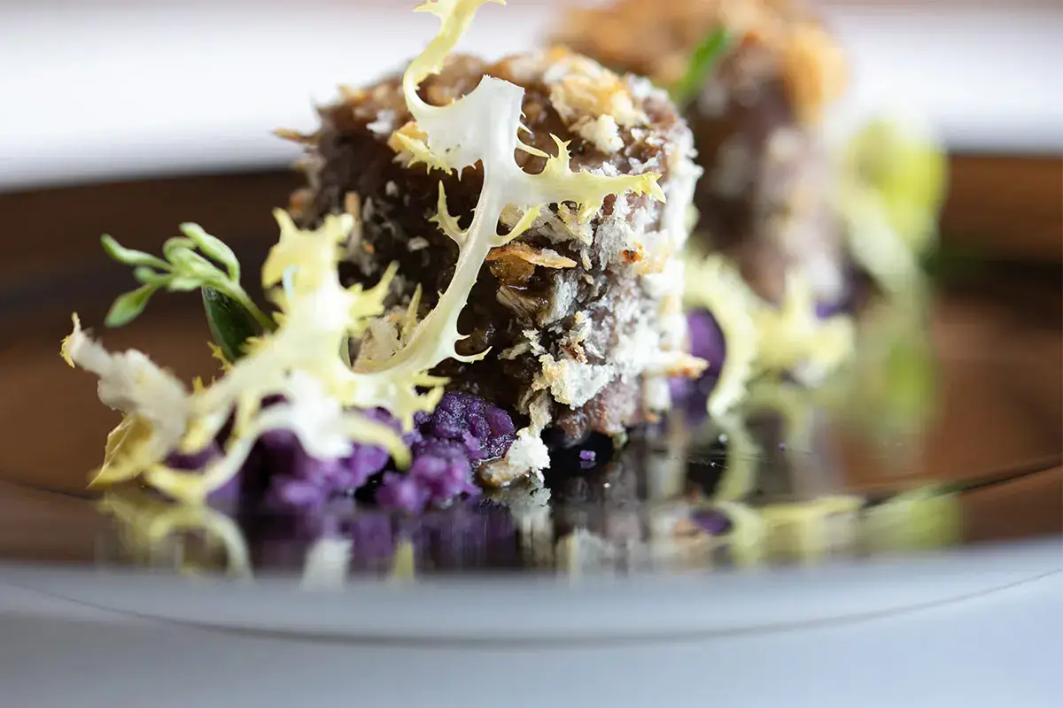 Sella d&rsquo;agnello in crosta di pane e erbe, con terra di patate viola e indivia riccia Sella d&rsquo;agnello in crosta di pane, terra di patate viola e indivia riccia