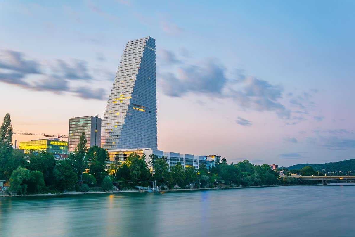 Vista al tramonto sulla riva del fiume Reno dominata dalla torre Roche Arte, architettura ed esperienze: ecco Bailea, la New York della Svizzera