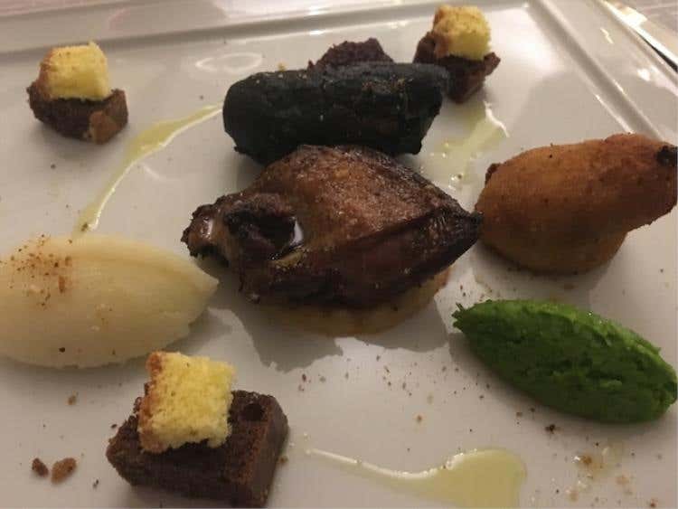 Piccione in due cotture: petto caramellizzato allo zucchero di canna fumè al miele, coscia ripiena al cioccolato di Modica in due tempure, quenelles arlecchino di piselli, barbabietola e cavolfiore alla nocciola