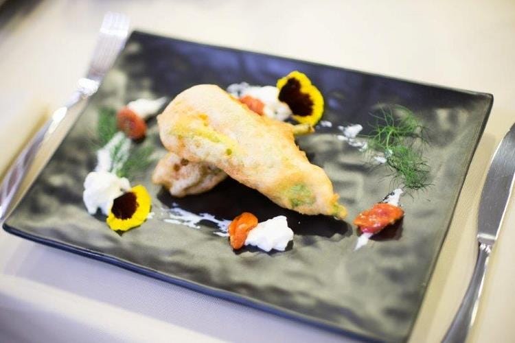 Fiori di zucca in tempura con farcitura alla mediterranea su crema di burrata e pachino confit