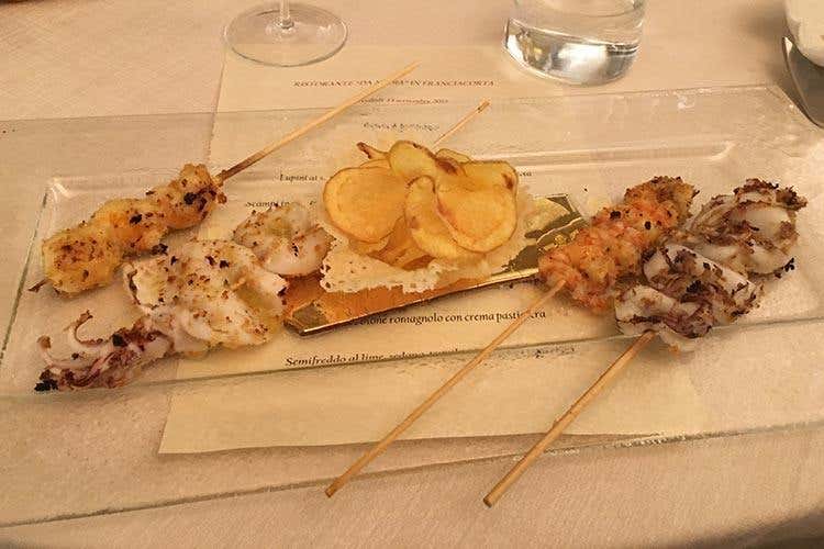 Spiedini di calamaretti, scampi sgusciati, mazzancolle e seppioline sul carbone, con cestino di Parmigiano Reggiano e chips di patate - Cambia la location ma resta la qualità 
La cucina di Nadia ora in Franciacorta