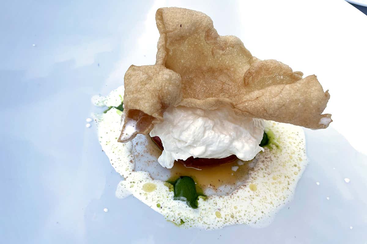 Burrata, tartare di pomodoro, pesto al basilico, polvere di cipolle di Tropea e frisella soffiata, completata con crema di burrata emulsionata con olio extravergine d'oliva